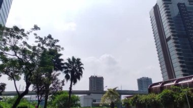 Jakarta 'daki yüksek binaların arasından geçen Mass Rapid trenin görüntüsü. Açık mavi gökyüzü.