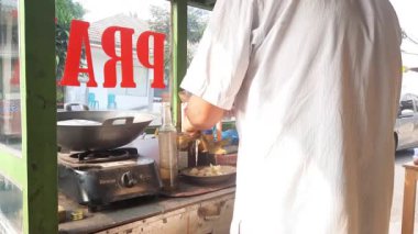 Jakarta, Endonezya - 3 Kasım 2023: Bir ketoprak satıcısı müşterisi için sipariş hazırlıyor. Ketoprak, tofu, sebze, pirinç keki ve fıstık sosundan oluşan bir vejetaryen yemeğidir.