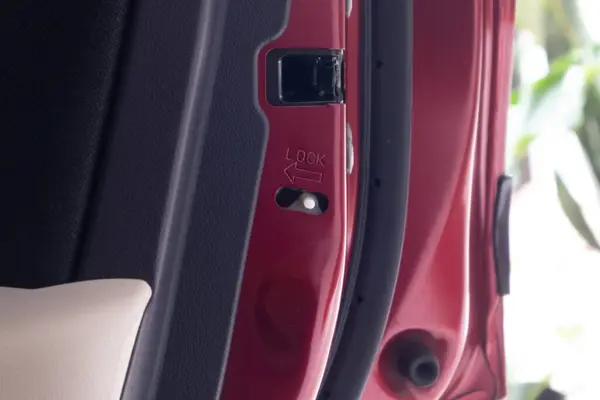 The child lock button in the red car's door. Lock button to prevent children from opening car doors.