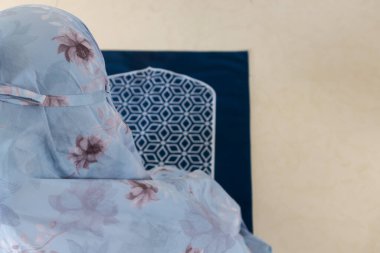 Müslüman bir kadın tesettüre oturmuş mükena denilen başörtüsü takıyor.