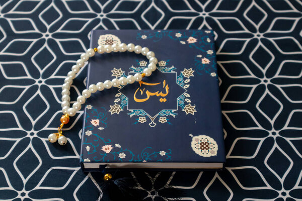 A Surah Yaseen or Yasin book and prayer beads on a prayer mat