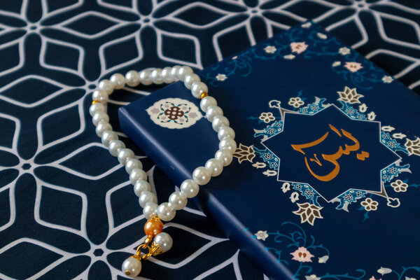 A Surah Yaseen or Yasin book and prayer beads on a prayer mat