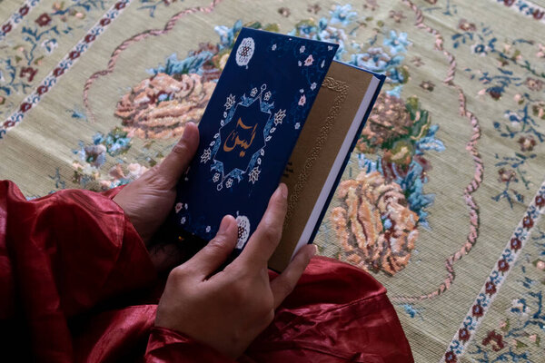 Close up view of a muslim woman holding the Quran or surah yaseen or yasin book