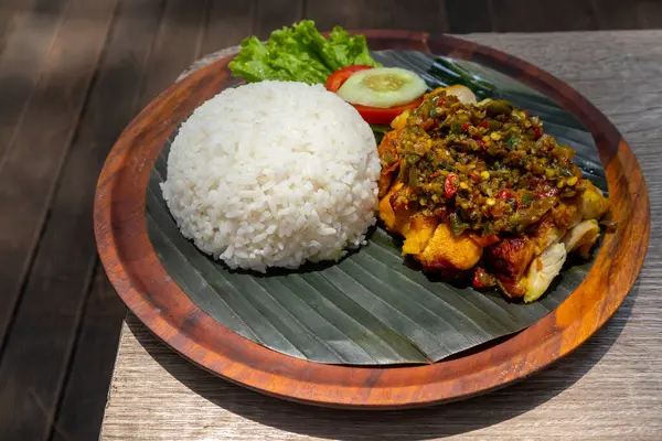 Smashed fried chicken with green chili sauce or Ayam geprek samba hijau served with steam rice on wooden plate