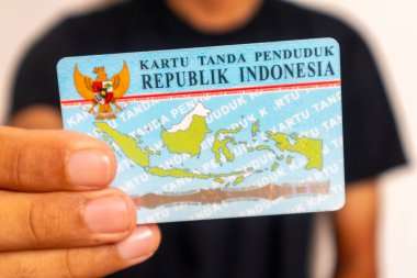 Jakarta, Indonesia - March 13, 2024: A man in black clothes holding The Indonesian identity card or Kartu Tanda Penduduk Indonesia or KTP clipart