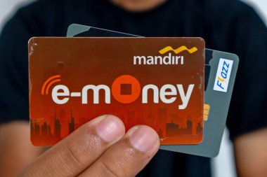 Jakarta, Endonezya - 13 Mart 2024: Siyah elbiseli bir adam elektronik para kartlarını ya da RFID Chip Technology ile çok işlevli işlem kartını elinde tutuyor
