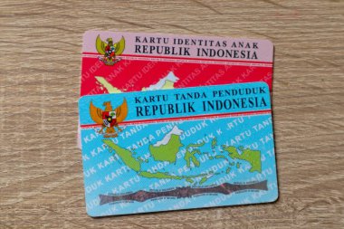 Jakarta, Indonesia - March 13, 2024: The Indonesian identity card and The Indonesian child identity card isolated on wooden background clipart