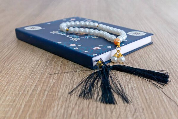 A Surah Yaseen or Yasin book and prayer beads on a wooden table