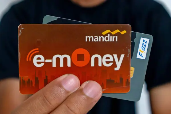 Jakarta, Endonezya - 13 Mart 2024: Siyah elbiseli bir adam elektronik para kartlarını ya da RFID Chip Technology ile çok işlevli işlem kartını elinde tutuyor
