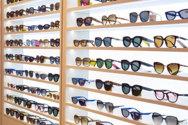 Mağaza vitrininde çeşitli güneş gözlüğü ve moda kıyafetlerinin görüntüsü