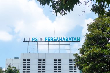 Jakarta, Indonesia - April 22, 2024: RSUP Persahabatan or Persahabatan Hospital building located in East Jakarta with blue sky and green trees. clipart