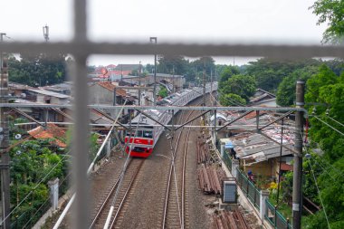Jakarta, Endonezya - 23 Nisan 2024: Güney Jakarta 'daki yerleşim alanlarından geçen banliyö treninin görüntüsü. Yaya köprüsünden görüldü..
