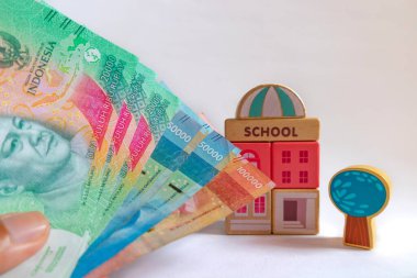 Endonezya rupia banknotları. Arkasında okul ahşap oyuncağı var. Eğitim masrafları konsepti.