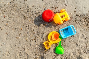 Güneşli bir günde kumdaki plastik plaj oyuncakları. Üst görünüm.