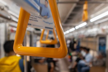 Banliyö trenindeki tırabzanın yakın görüntüsü. Toplu taşıma aracının arka planı bulanık asma kolu.