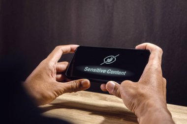 Gözü şaşı ekranda akıllı telefon kullanan bir adam. Sosyal medyada ya da web sitesinde açık içerik. Kısıtlanmış içerik.