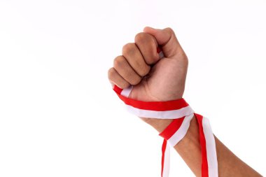 Güçlü kolları ve sıkılmış yumrukları olan bir adam Endonezya bayrağının sembolü olarak kırmızı ve beyaz kurdele tutuyor. Endonezya Bağımsızlık Günü konsepti.