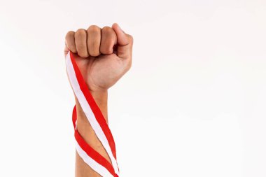 Güçlü kolları ve sıkılmış yumrukları olan bir adam Endonezya bayrağının sembolü olarak kırmızı ve beyaz kurdele tutuyor. Endonezya Bağımsızlık Günü konsepti.