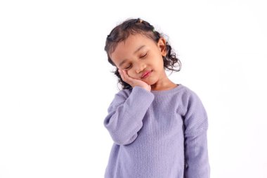 Beyaz bir arka planda, gözleri kapalı poz veren küçük tatlı bir Asyalı kız.