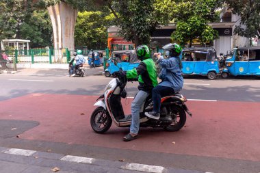 Jakarta, Endonezya - 10 Ağustos 2024: Çevrimiçi motosikletli bir taksi şoförü Jakarta 'da bir yolcu alma noktasından yolcu alıyor