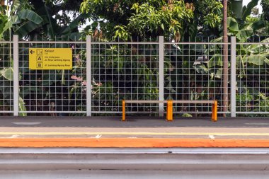 Jakarta, Endonezya - 10 Ağustos 2024: Jakarta 'da bir bankta ve tabelalı tren istasyonunda tren yolcuları için bekleme alanı