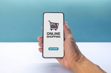 Çevrimiçi alışveriş için cep telefonu tutuyorum. Cep telefonu ekranında alışveriş arabası simgesi.