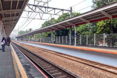Jakarta, Endonezya - 18 Ağustos 2024: Trenin istasyona varmasını bekleyen yolcular. Jakarta 'da bir banliyö treni platformunun görüntüsü.