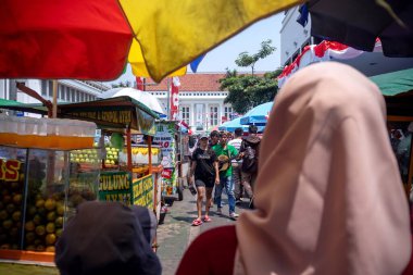 Jakarta, Indonesia - August 18, 2024: Tourists walk among of street vendors at the tourist attraction of Kota Tua Jakarta clipart