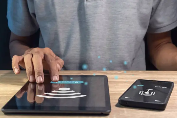 Kişisel yardım noktasını kullanarak cep telefonu ve tablet bilgisayar arasındaki interneti paylaşan adam
