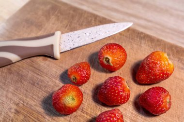 Taze olgun çilekler ve tahta kesme tahtasında bir bıçak.