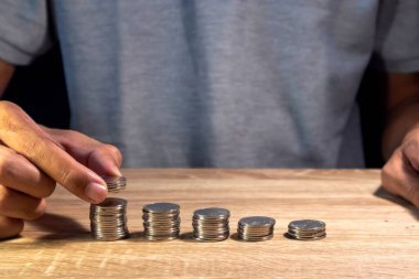 İnsan, maliyeti ya da bütçeyi hesaplamak için ahşap masada yığınla para yapar.
