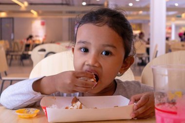 Fast food restoranında yemek yiyen güzel bir Asyalı kız.