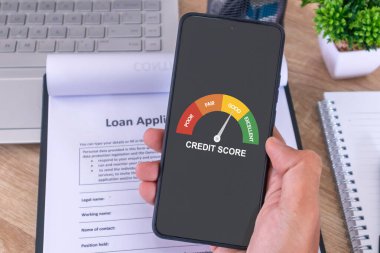 Kredi skorunu kontrol etmek ve bankaya kredi başvurusunda bulunmak için cep telefonu tutan bir erkek.