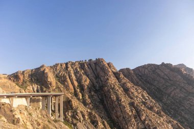 Aerial view of rocky mountains and blue sky with highway in Taif city, Saudi Arabia clipart