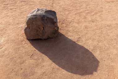 Büyük bir taş ve kuru zeminde gölgesi.