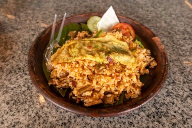 Çamur tabakta muz yaprağı tabanlı yumurta ve sebzeli kızarmış pilav.