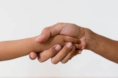 Bir babanın ve küçük kızının elleri beyaz arka planda el sıkışıyor.