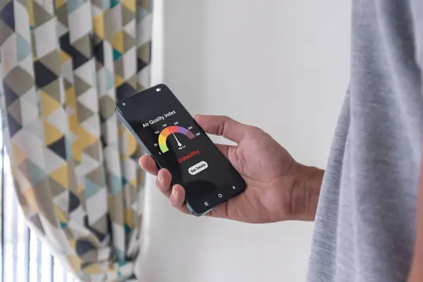 Adam akıllı telefonundaki uygulamayı kullanarak hava kalite indeksini kontrol ediyor