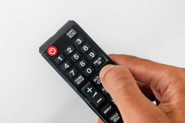 Beyaz arkaplanda birçok düğmesi olan bir televizyon kumandası.