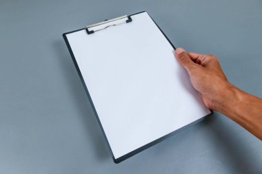 Gri zemin üzerinde boş beyaz kağıt olan bir pano tutuyordu.