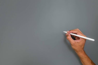 Gri arkaplana bir şeyler yazmak için elinde kalem ya da kalem tutuyordu.