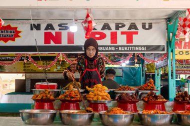 Batı Sumatra, Endonezya - Nisan 04, 2025: Bukit Tinggi 'de geleneksel bir gıda standında tipik Minangkabau mutfağı satan bir kadın.