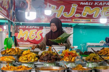 Batı Sumatra, Endonezya - 4 Nisan 2025: Bukit Tinggi 'de tipik bir Minangkabau yemeği olan Nasi Kapau' yu satan bir kadın