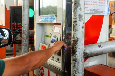 Pekanbaru, Endonezya - 14 Nisan 2025: Bir otomobil sürücüsü geçiş kartı tutuyor ve geçiş kapısında ödeme yapıyor.