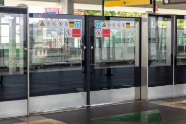 Kitle Hızlı Geçiş Tren İstasyonu Jakarta 'da çeşitli güvenlik uyarısı etiketleriyle Platform Ekran Kapısı (PSD) veya Platform Sınır Kapısı (PED)