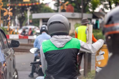 Jakarta, Endonezya - 02 Mayıs 2025: Güney Jakarta 'daki demiryolu kavşağında kask takan motosikletliler