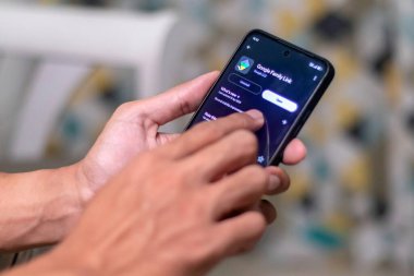 Jakarta, Endonezya - 11 Mayıs 2025: Bir baba akıllı telefonuna çocuklarının cihazlarındaki çevrimiçi aktiviteleri yönetmek için Google Family Link uygulamasını yükledi