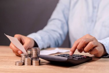 Elinde alışveriş makbuzu tutan ve maliyetini hesap makinesiyle hesaplayan bir kadın.