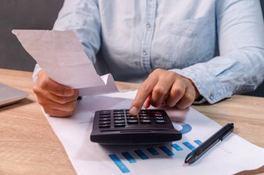 Bir kadın alışveriş masraflarını masadaki hesap makinesiyle hesaplar.