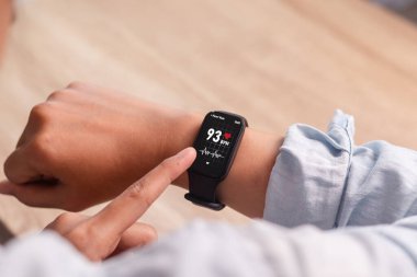 Bir kadın akıllı saatini kullanarak kalp atışlarını ölçer.